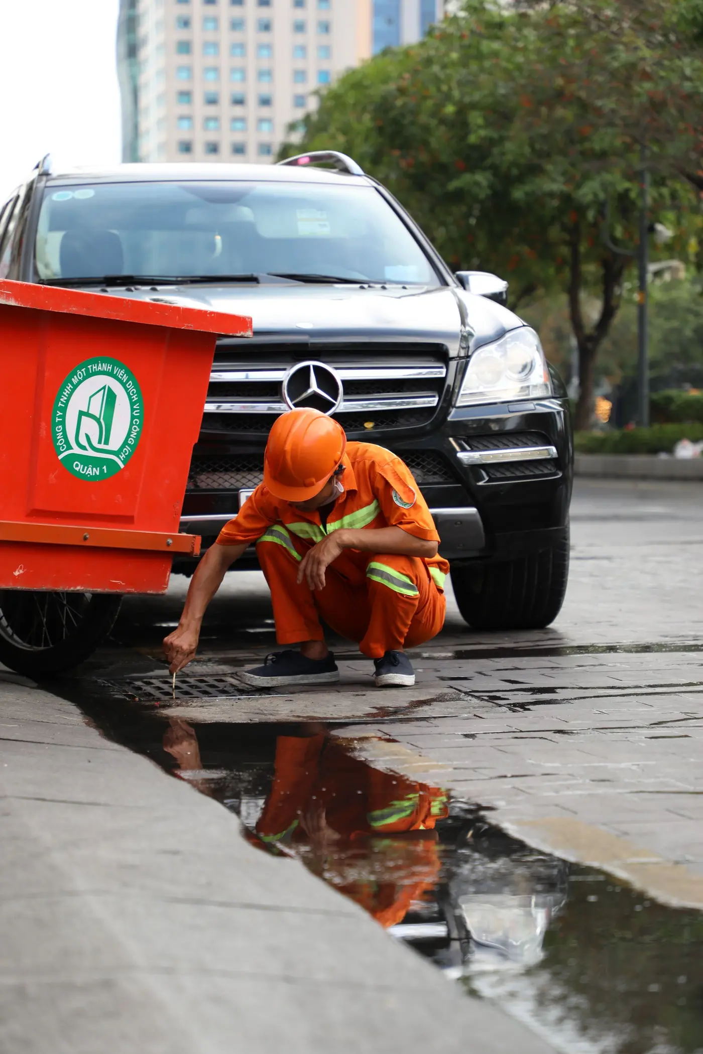 Maintenance worker looking into a street drain opening before clearing a blockage