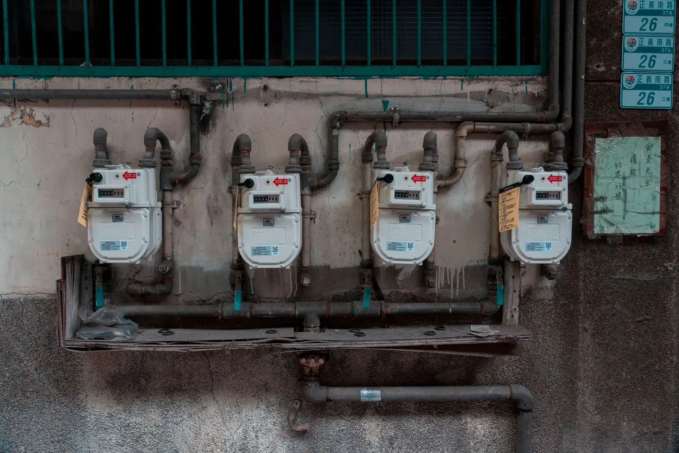 Gas meters and connected piping mounted on the exterior wall of a building