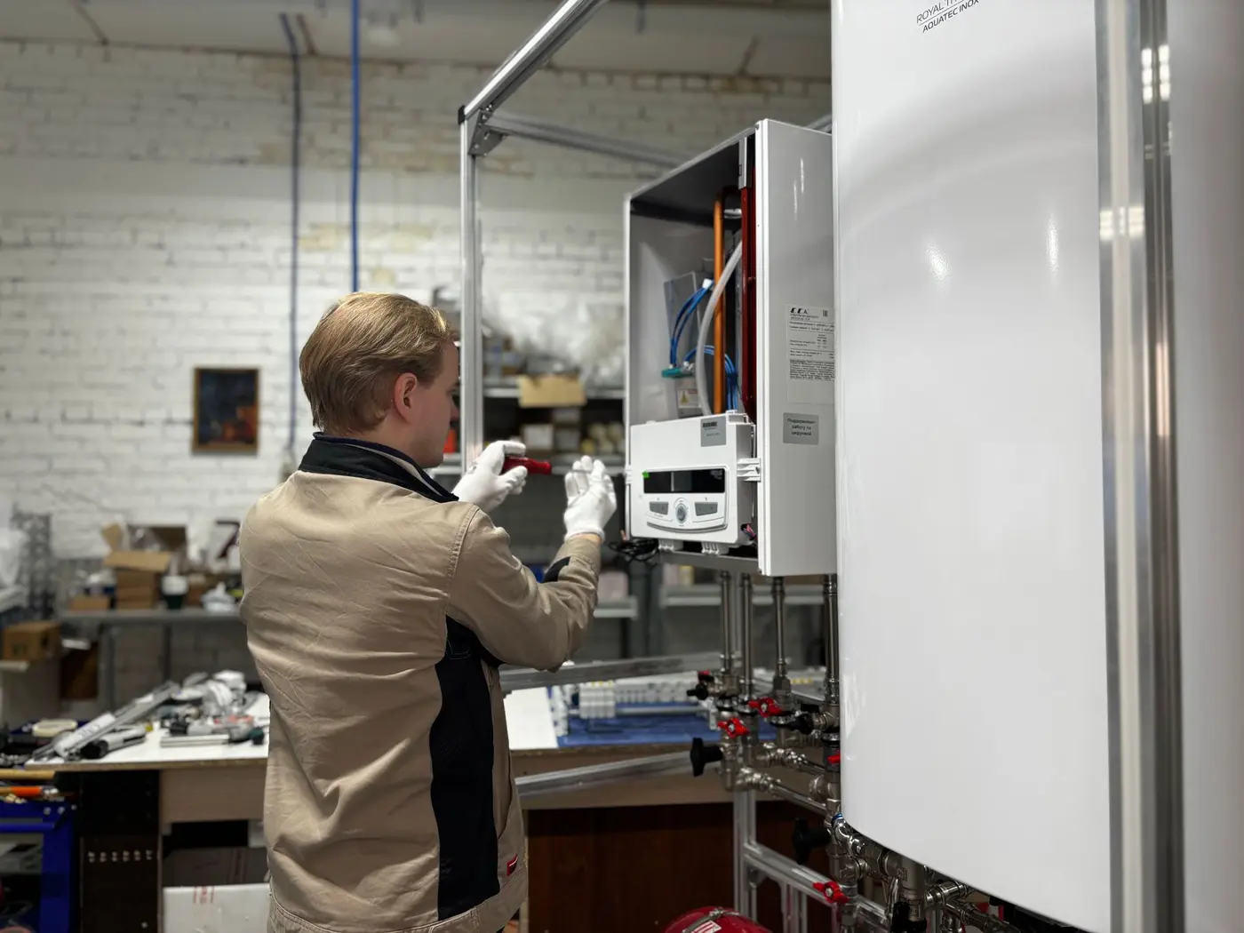 Technician connecting the control panel and pipework on a storage water heater tank