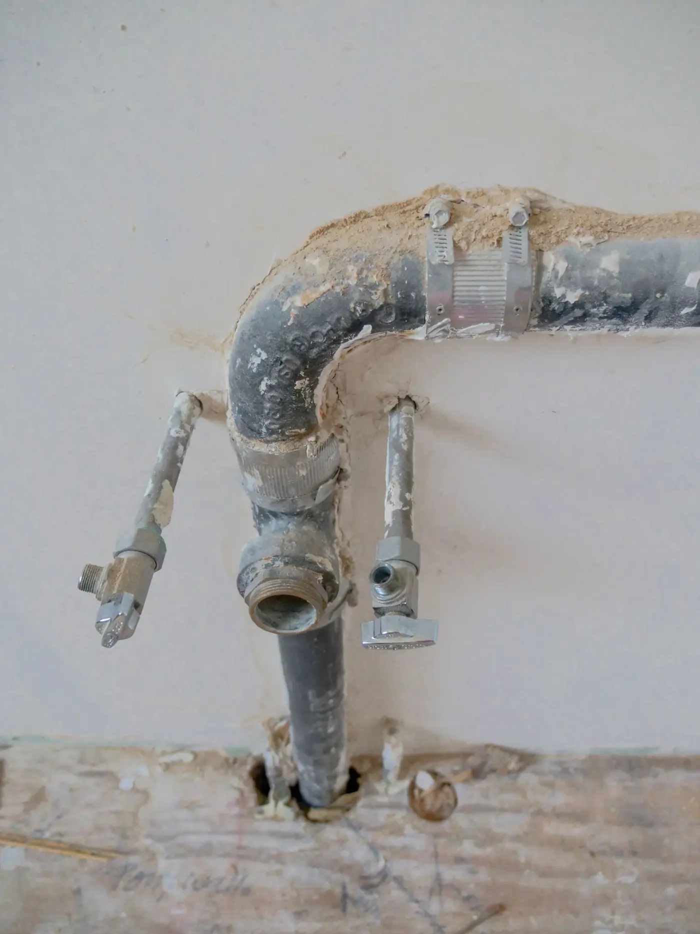 Old pipe stub-out and shut-off valves exposed in a wall opening during renovation