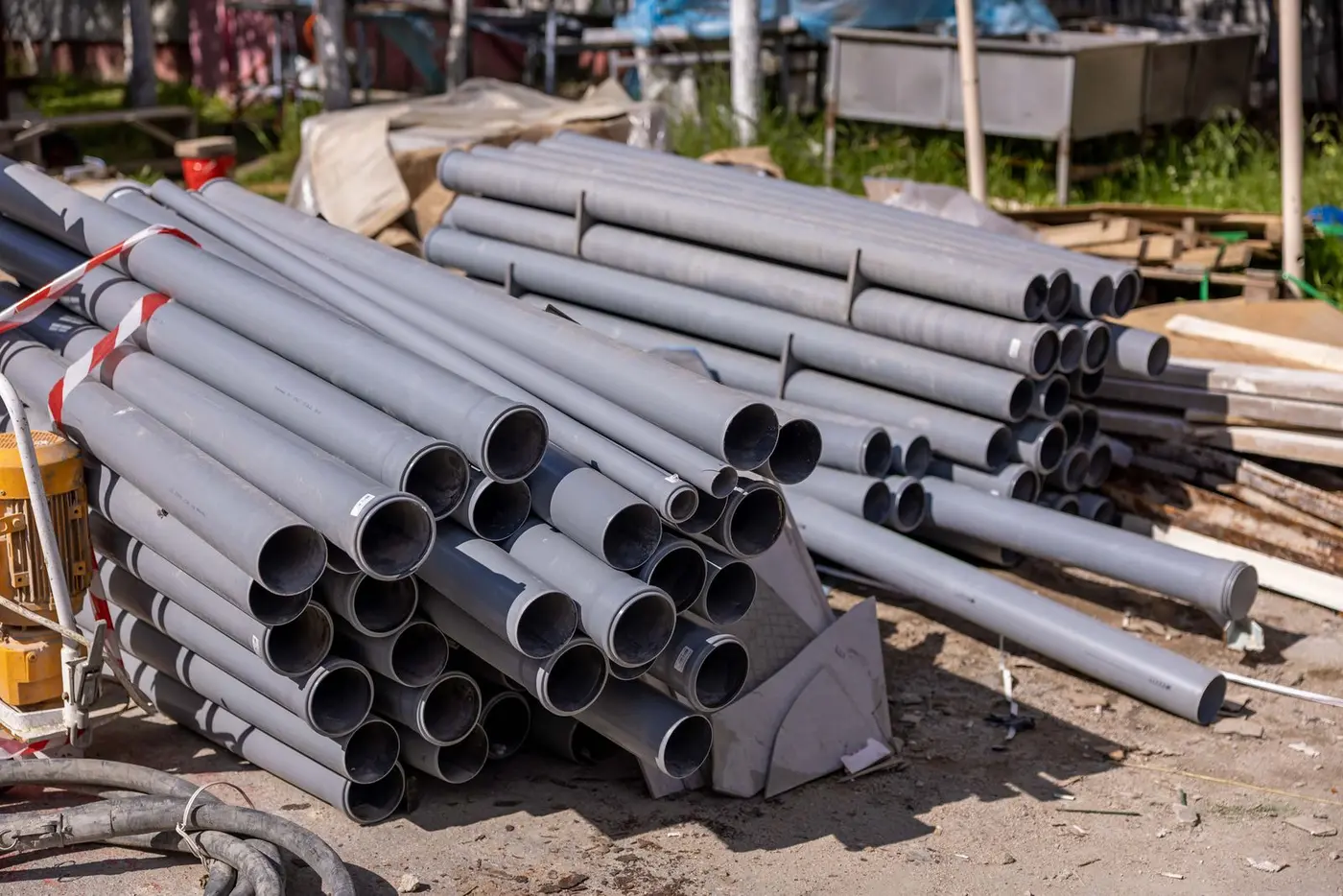 Stack of grey plastic pipe lengths staged at a job site for a replacement