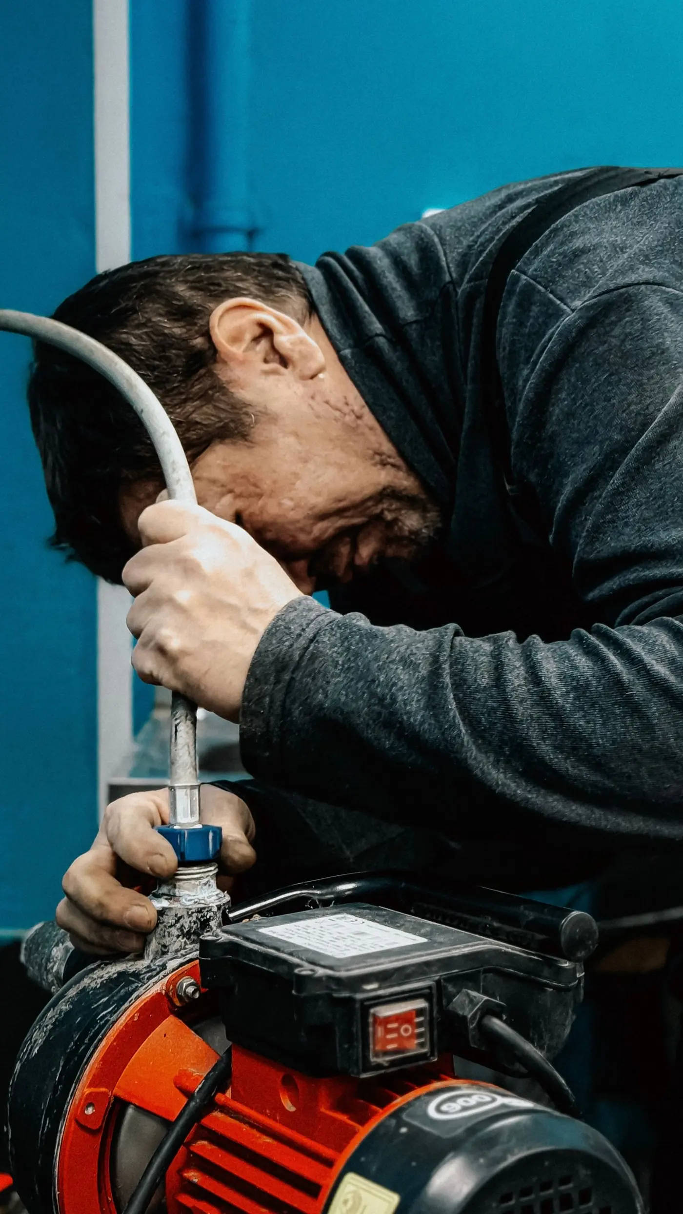 Technician's hands wrenching on a submersible pump motor during a service