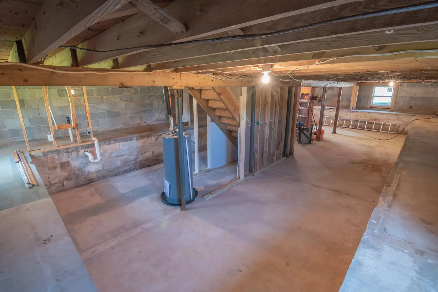 Unfinished basement with exposed joists and rough-in plumbing, the kind of space a sump pit goes in