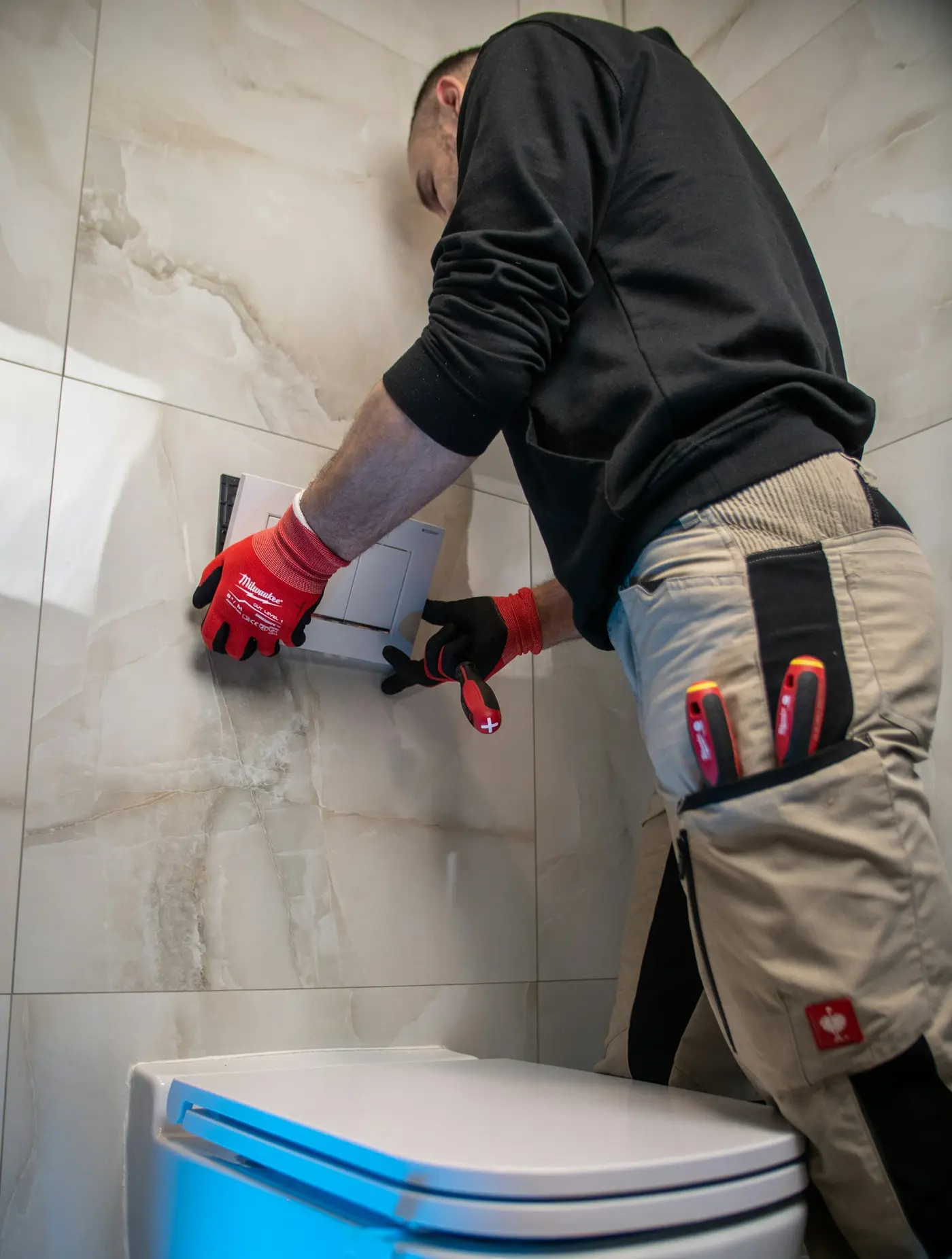 Plumber in work gloves setting a toilet bowl during an installation