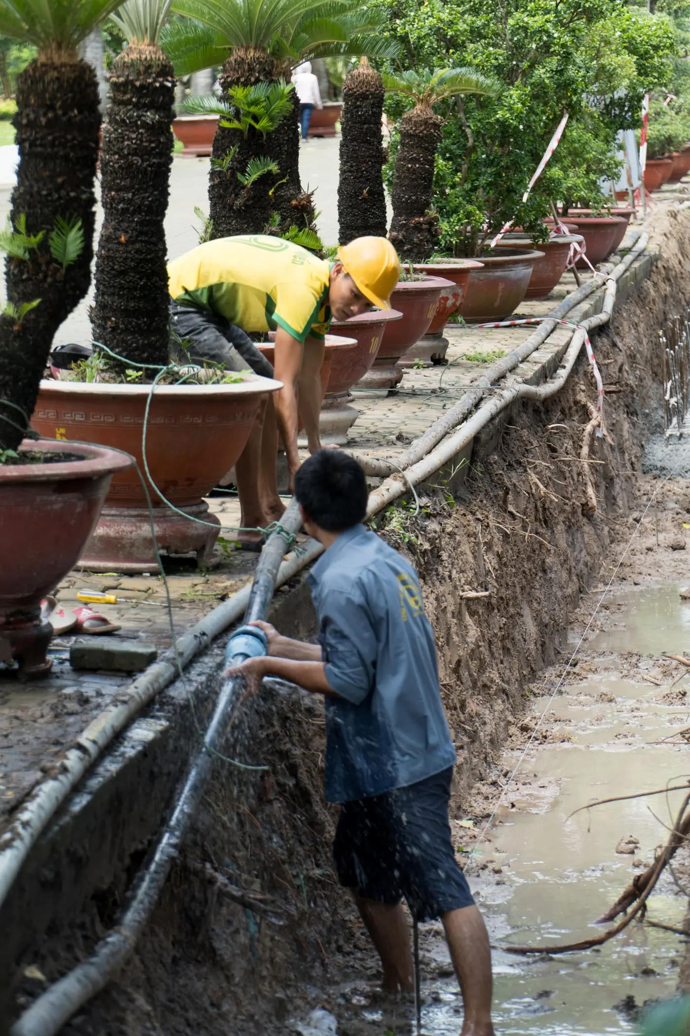 Two workers in an open ground trench joining a water service pipe
